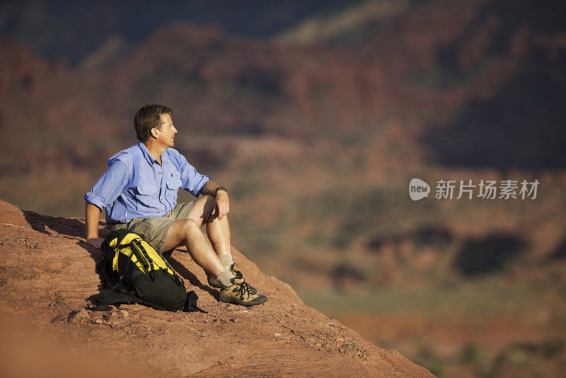 男性徒步旅行者坐在岩石上看风景