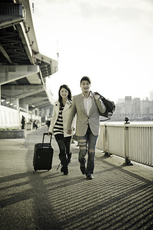 年轻时尚的夫妇带着行李跑步