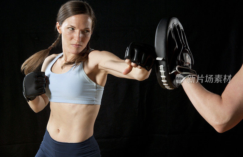 女运动员与教练练习拳击。