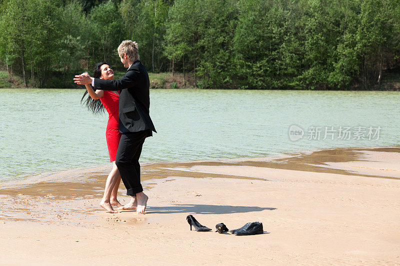一对相爱的年轻情侣在沙滩上赤脚跳舞