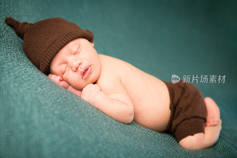 睡着的新生儿戴着针织帽和尿布套