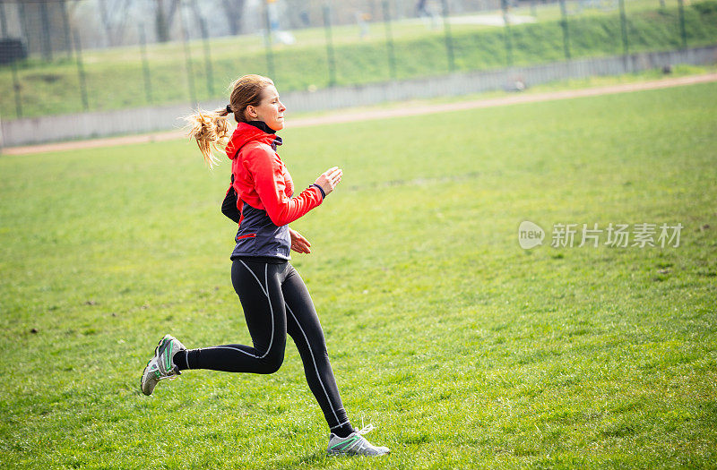 年轻女子在田径跑道上慢跑，过着健康的生活
