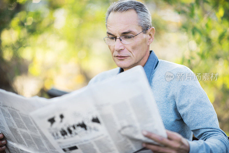 读报纸的成年人。