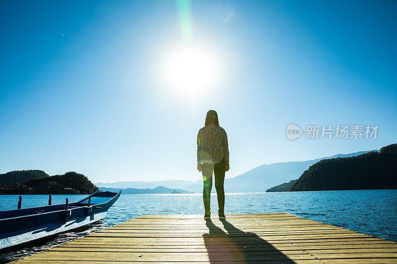 站在湖边码头上的女人