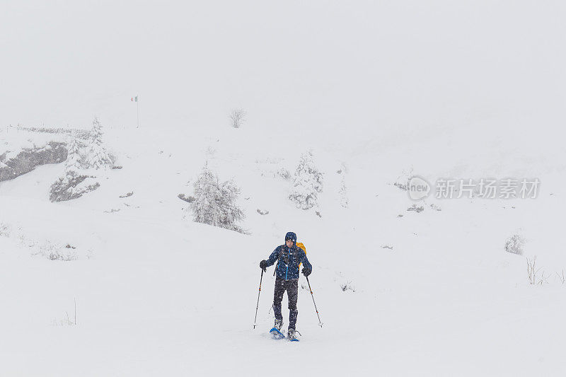 穿着雪鞋在多雾的雪地上行走的徒步者