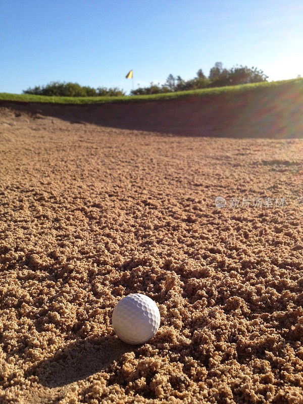 高尔夫球躺在有果岭和球柱的沙坑里