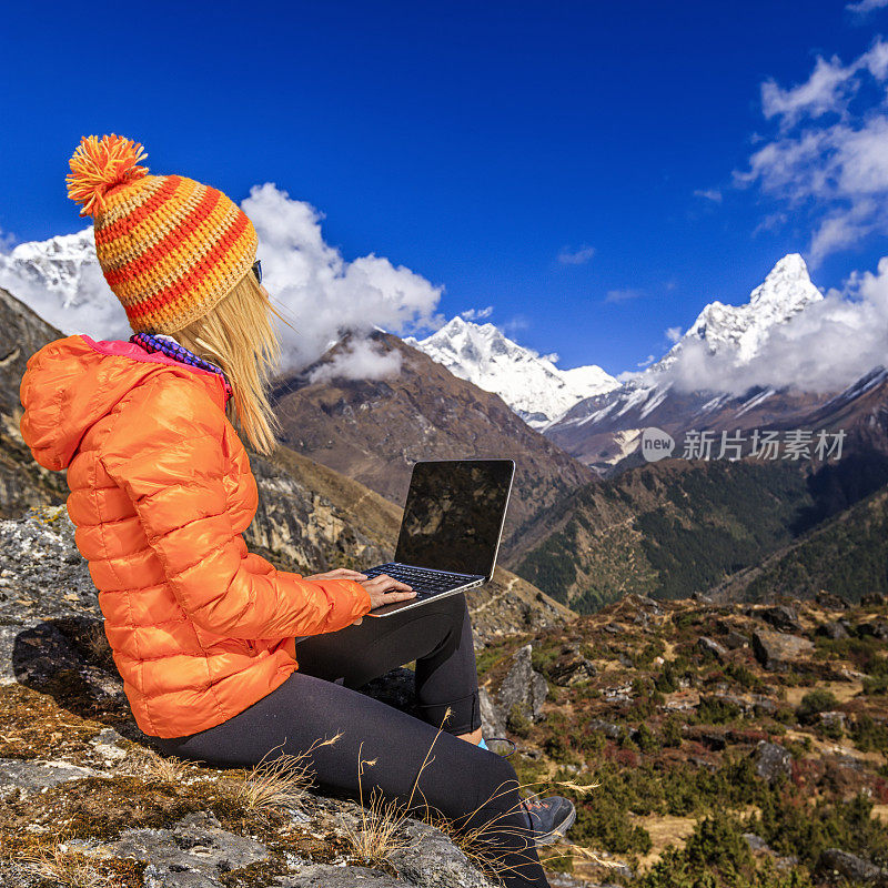一名年轻女子在尼泊尔喜马拉雅山使用笔记本电脑