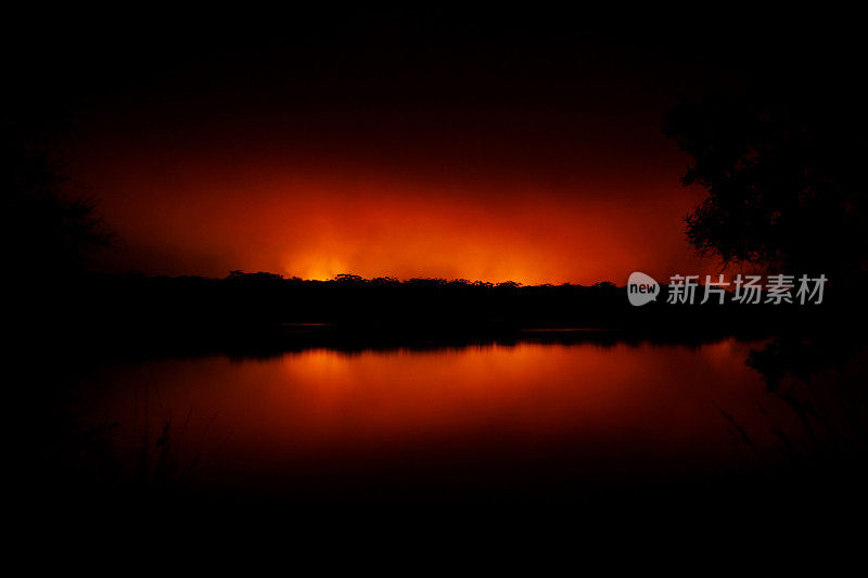 远处的山火在夜晚倒映在湖面上