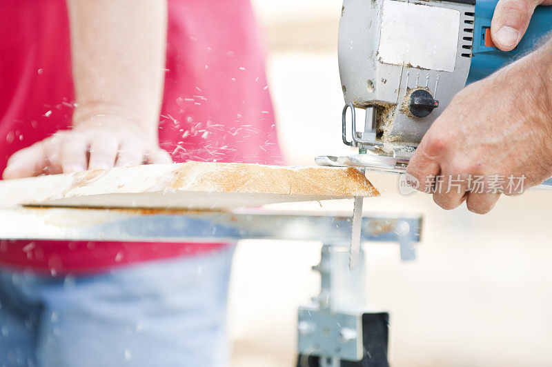 一个人用拼图锯切一块木板