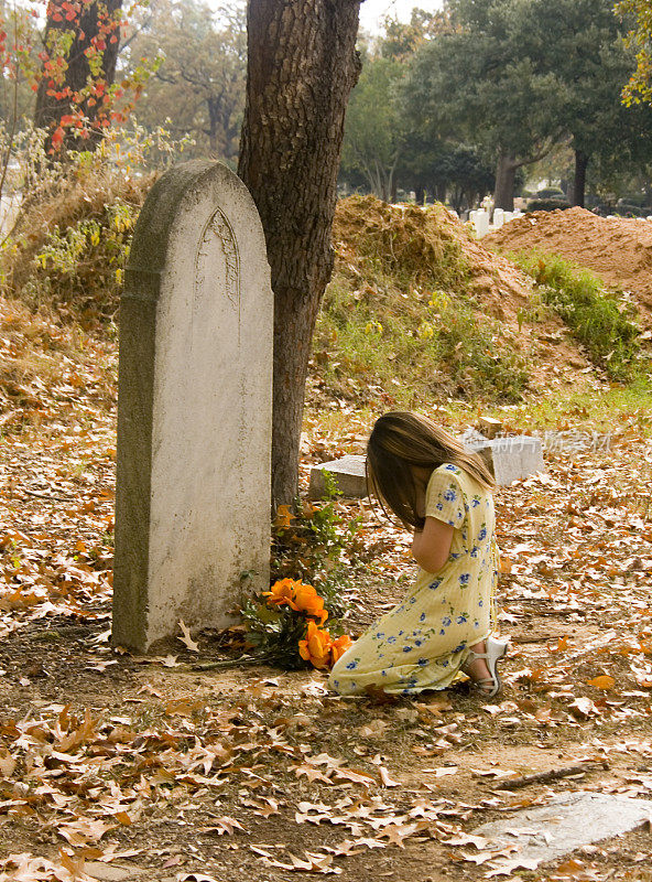 小女孩跪在坟墓旁