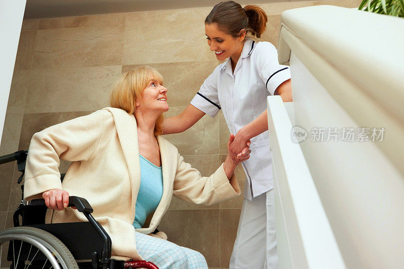 一名护士帮助年老的病人从轮椅上爬起来