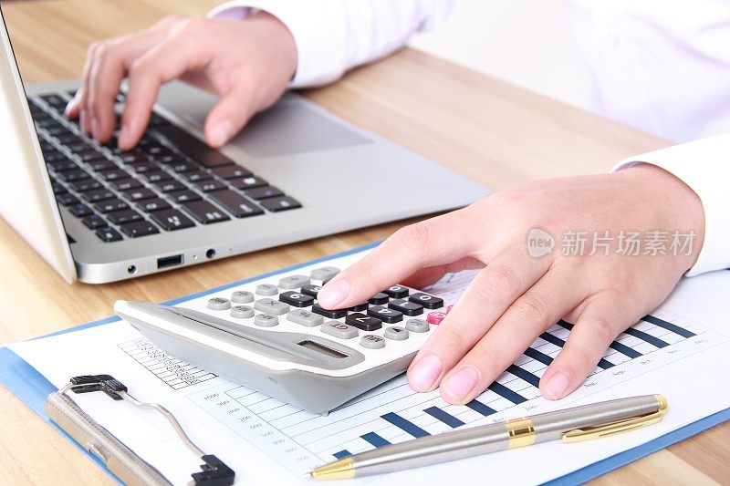 使用计算器和笔记本电脑的商务女性