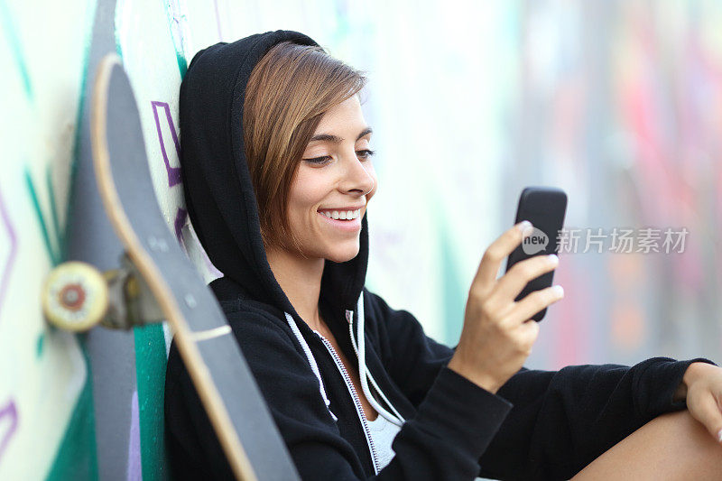 年轻的滑冰者快乐的少女使用智能手机