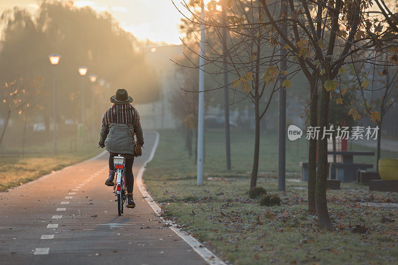 秋天的风景与波西米亚匿名女子骑老式城市自行车