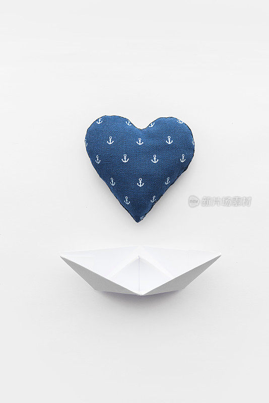 纸船在白色的哑光背景和心脏与一个锚