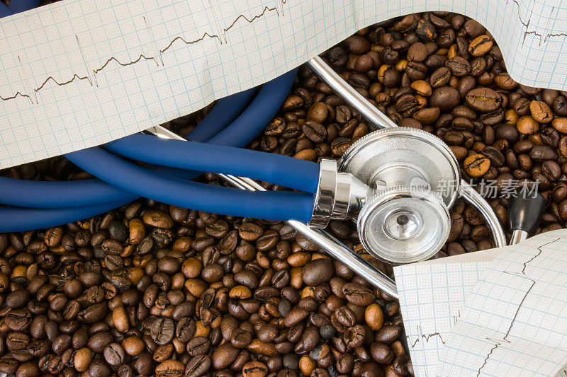 咖啡或咖啡因与心律失常(心律不齐)。听诊器和心电图带咖啡豆背景。饮用咖啡或咖啡因对心律失常发展的影响和风险