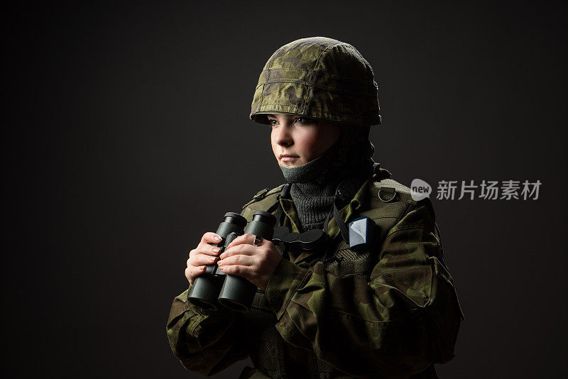 手无寸铁的女人的肖像。年轻的女兵用双筒望远镜观察。战争、军事、军民观念