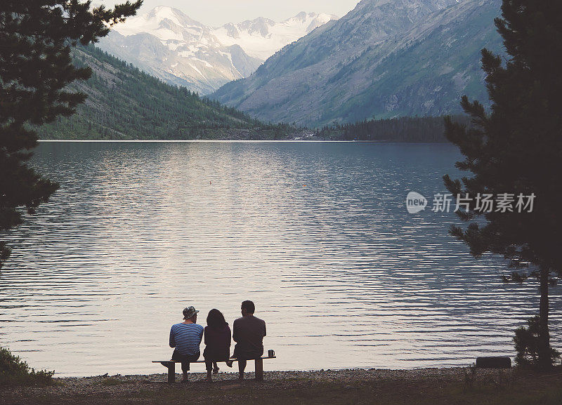 游客们坐在高山湖岸边的长椅上