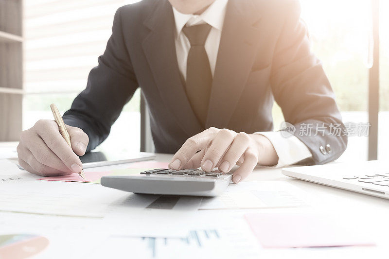 财务概念，财务控制审计人员在计算器上计算企业财务数据。