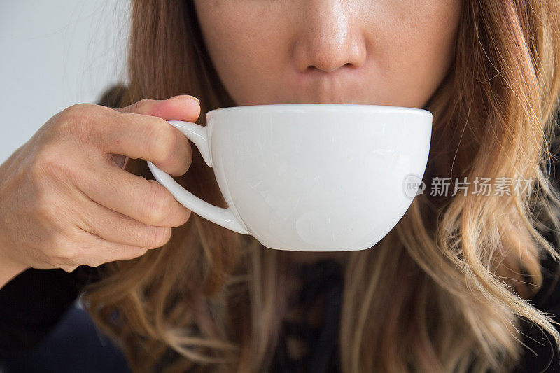 紧靠放松的年轻女子双手在咖啡厅喝着清晨的热茶、咖啡杯。