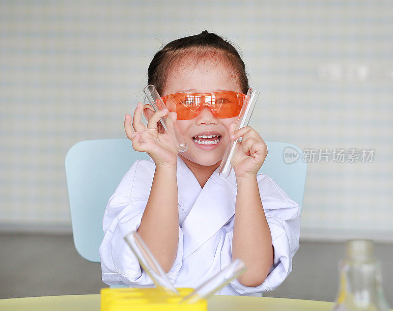 亚洲儿童在科学家制服持试管与液体隔离在白色背景，科学家化学和科学教育理念。