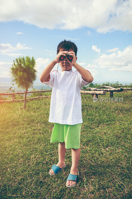 亚洲男孩透过望远镜看。孩子放松的假期。复古的基调。