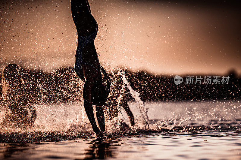 日落时分，一个女人在海里倒立。