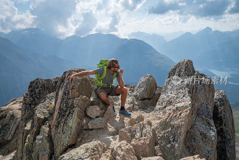 年轻人攀登山道上的岩石，以达到顶峰;人们户外活动概念拍摄于瑞士