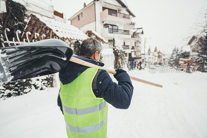 成熟的家伙拿着雪铲去清理雪