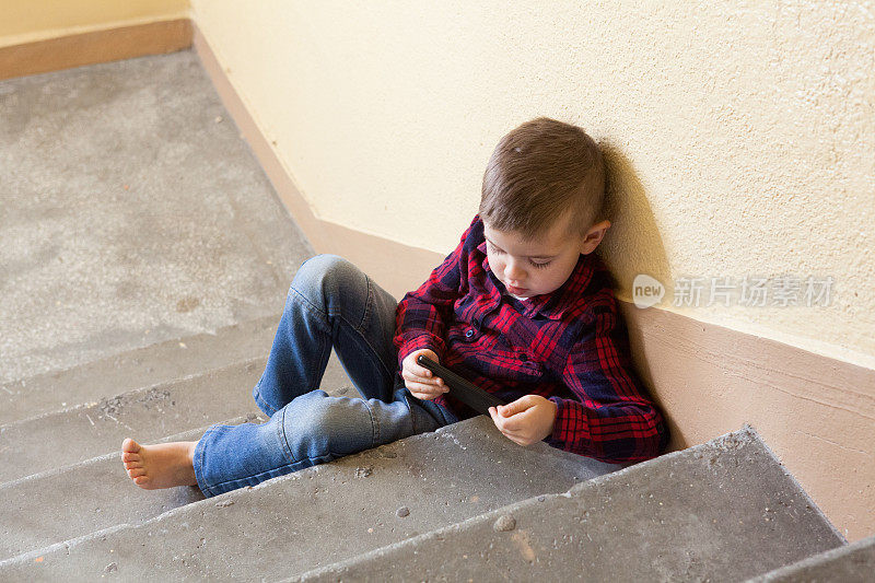 一个孩子在楼梯间打电话。