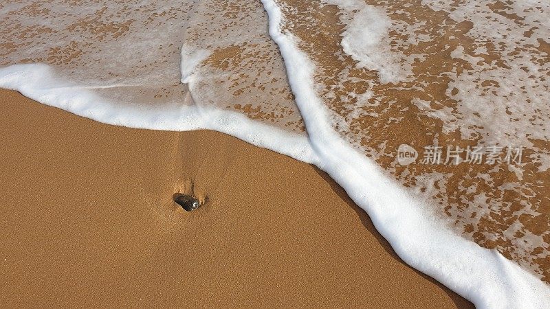 海水中的卵石在沙滩上激起泡沫