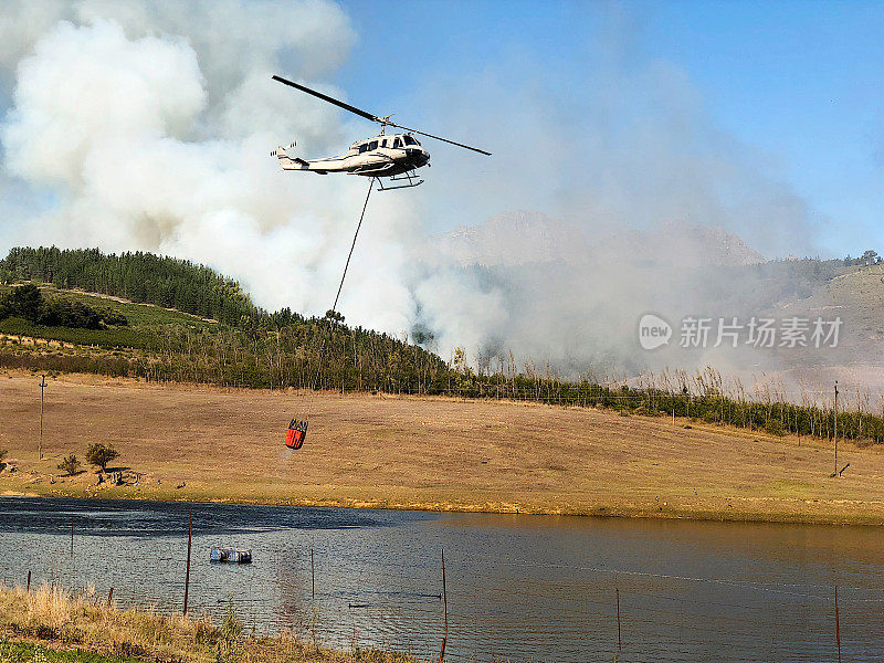 救援直升飞机填满飞向林地的火场侧面