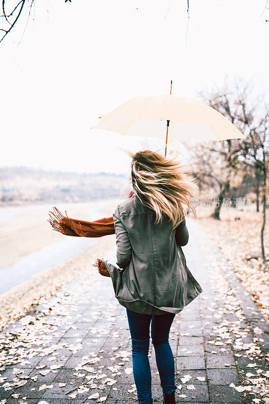 风咆哮周围的金发女性与伞
