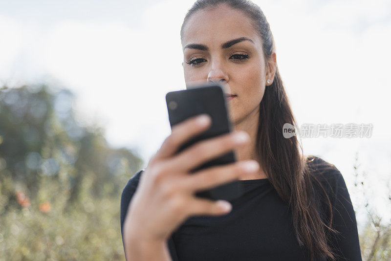 一个女人在户外使用智能手机的低角度视图