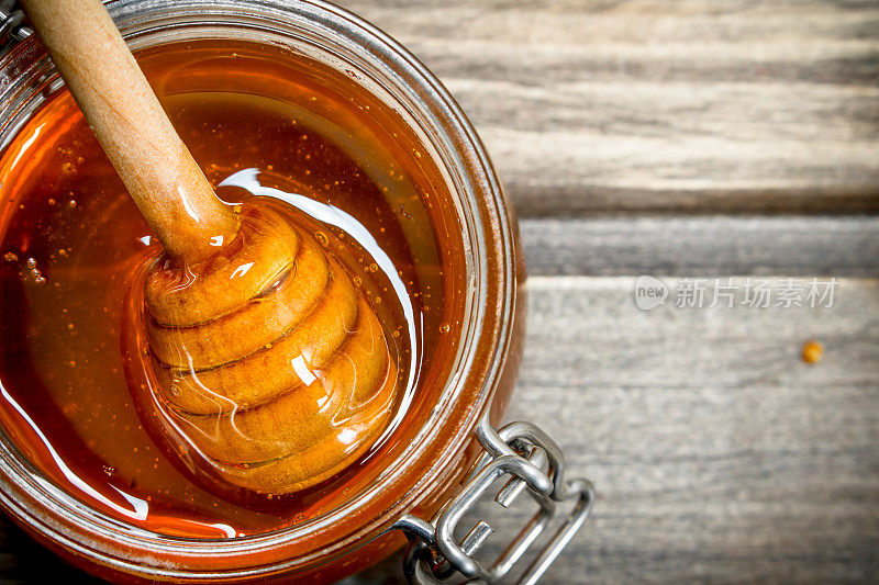 用勺子把新鲜蜂蜜装在玻璃罐里。