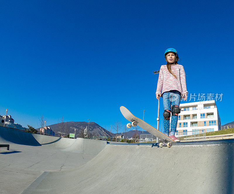 小女孩站在滑板公园的坡道边上