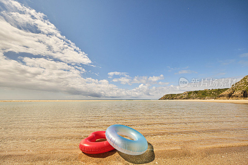 红心形状，圆形的蓝色橡胶环在清澈的浅海边，在佩恩范德海滩，康沃尔在一个田园诗般的六月天。