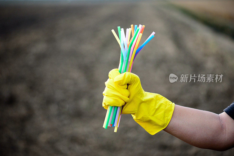 手持塑料吸管手套的手的特写——生态产业理念