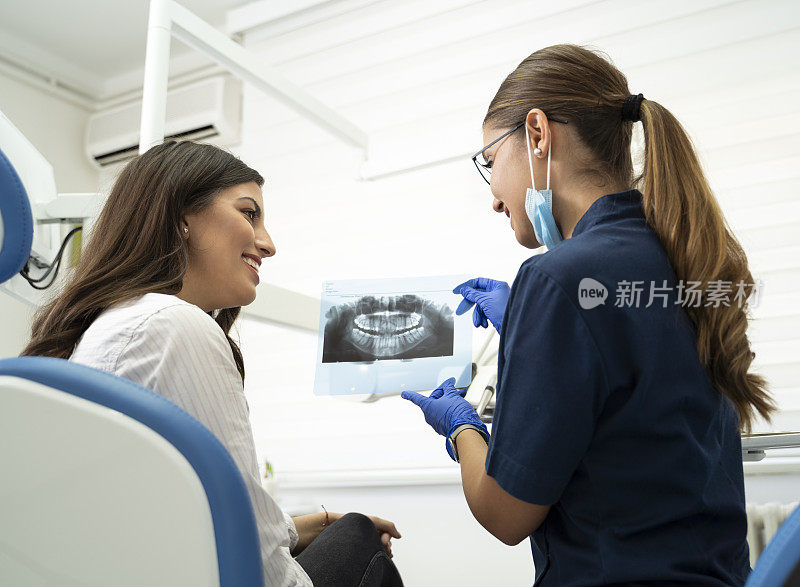 护士给病人女孩看她牙齿的x光片，他们一起微笑