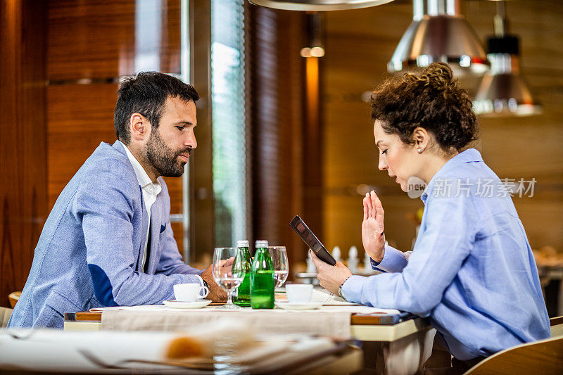 女商人在一家高级餐厅与同事聊天时使用手机