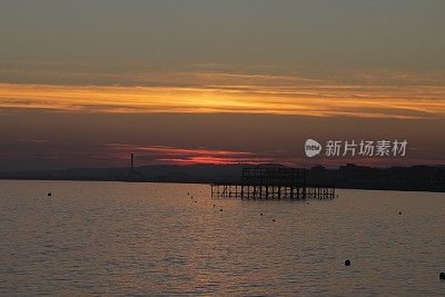 布赖顿西码头与戏剧性的日落天空在海上和城市沿海天际线布赖顿，东苏塞克斯，英国，从布赖顿码头，布赖顿海滩的黄昏照片