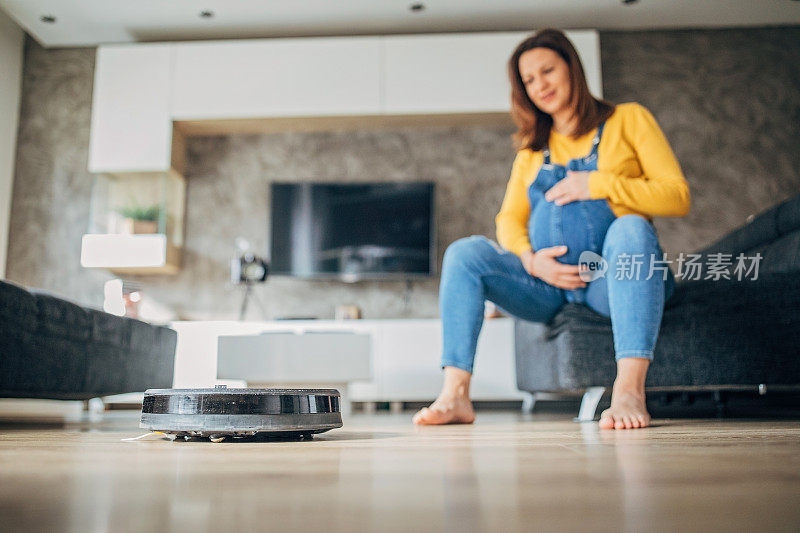 孕妇休息时，机器人真空吸尘器打扫地板
