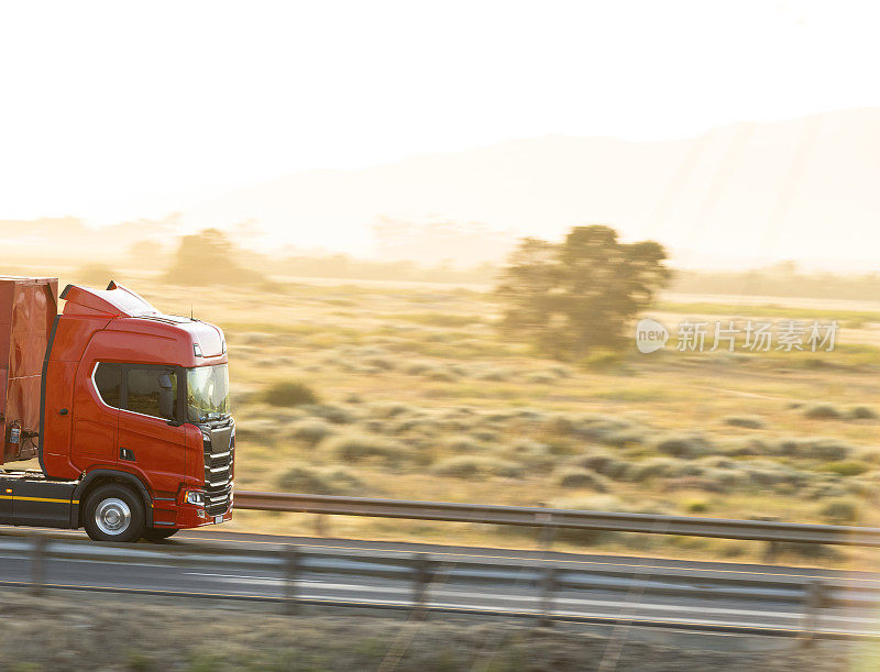 运动模糊的红色卡车在高速公路上加速在日出