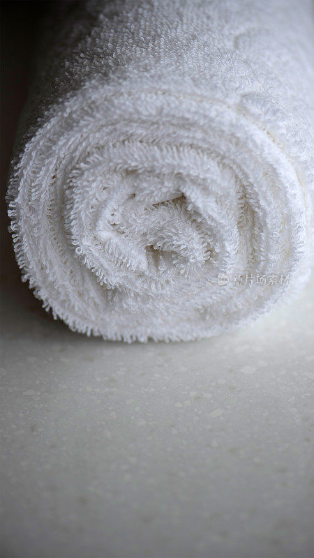 大理石台面上放着干净的白色毛巾、卷好的纺织品毯子