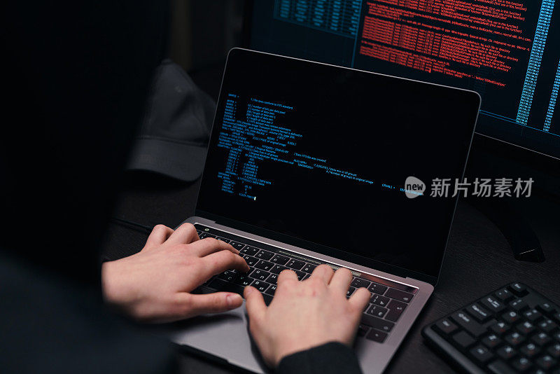 这是黑客在笔记本电脑上输入程序代码的双手特写。