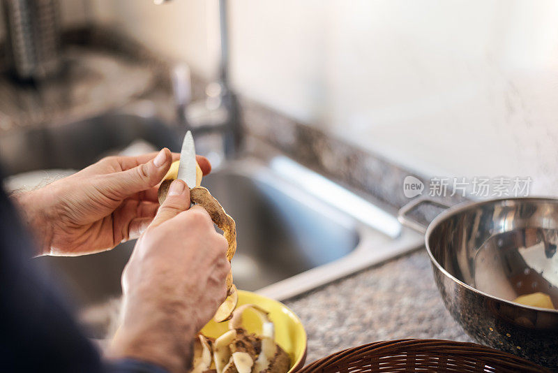 隔离烹饪:一名男子在煮土豆之前剥土豆皮