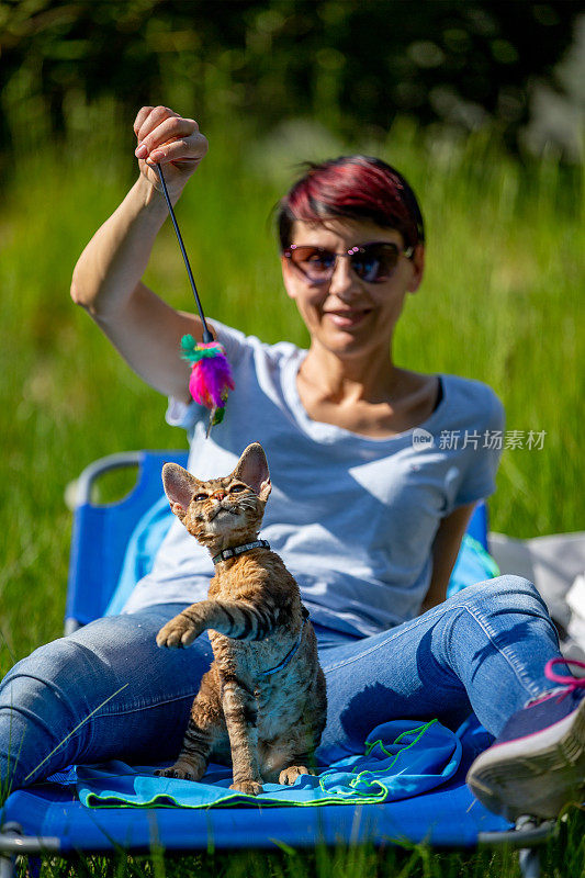 中年妇女玩和放松与她的小猫在户外在农村场景-库存照片