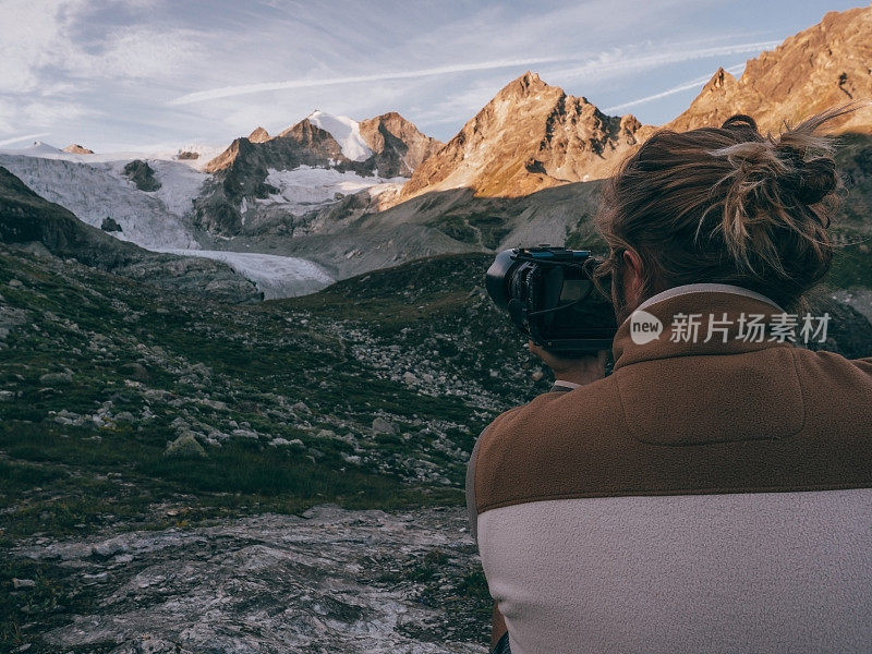 摄影师用单反相机拍摄日出的山峰和冰川
