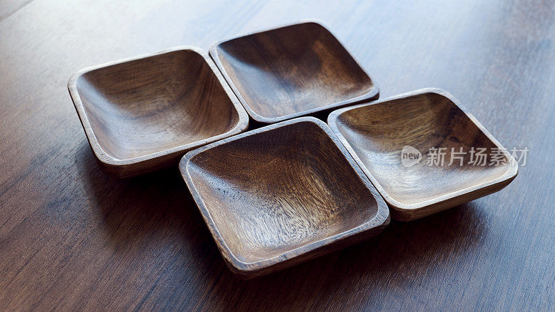 厨房用的木器、碗、盘子放在木桌上。自然菜品理念，健康生活方式。木材纹理的。木eco-ware。棕色木桌的背景上放着沙拉碗