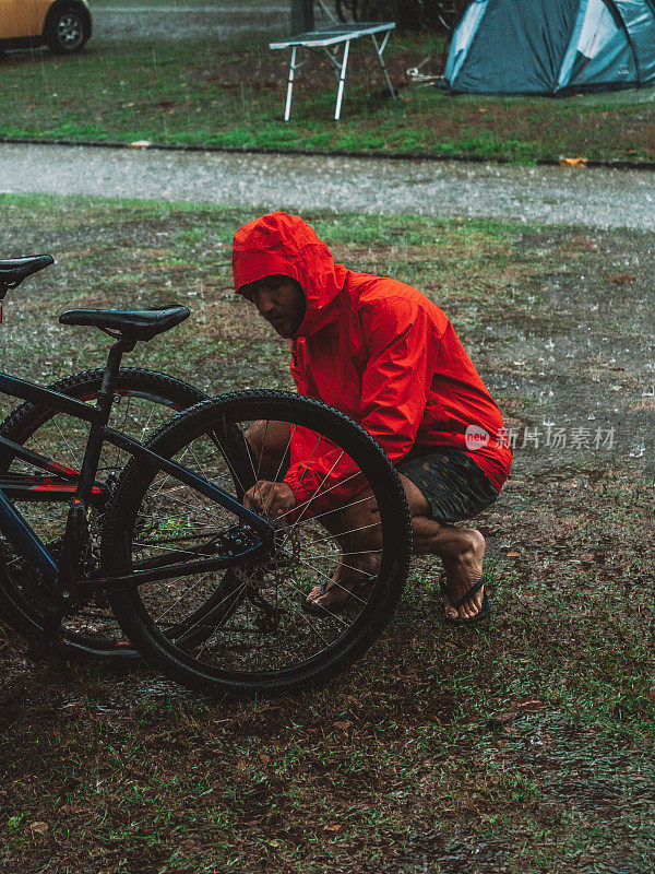 一名男子在暴雨中修理山地车